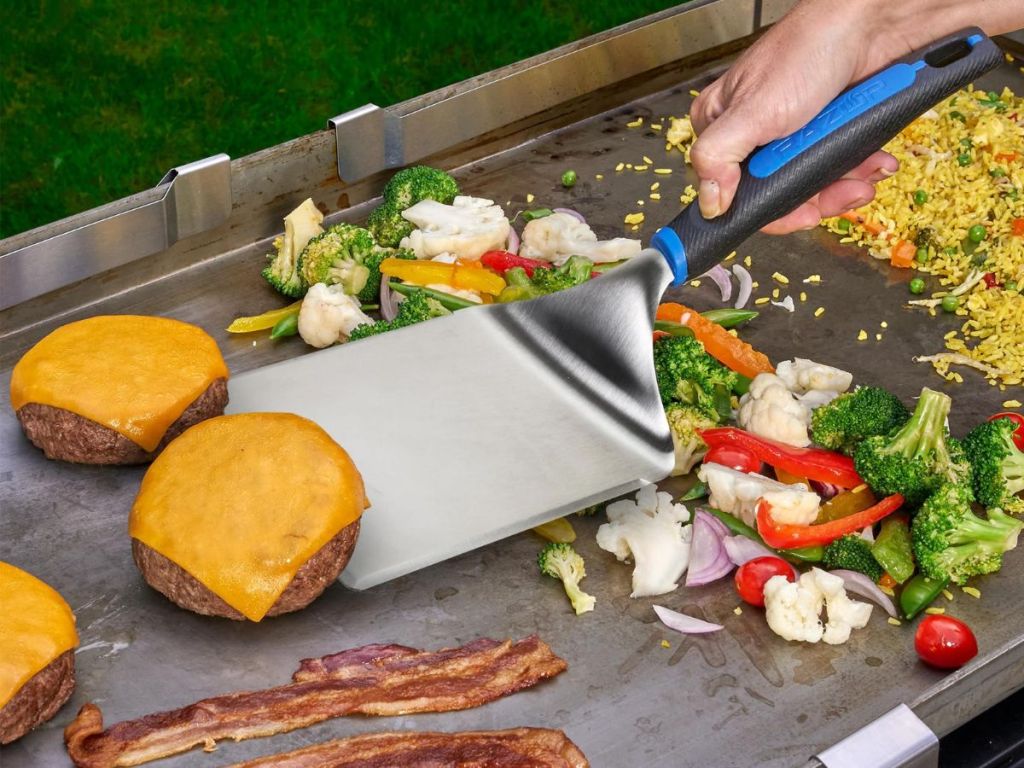 Mr BBQ Wide Spatula neing used to flip burgers on a griddle