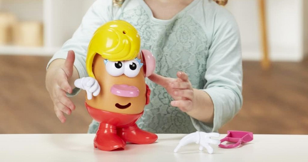 kid playing with Mrs. Potato Head toy on table