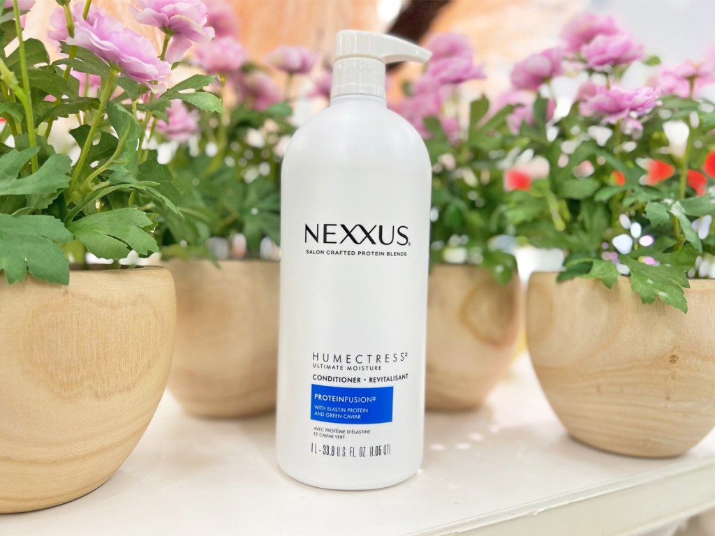 large white bottle of Nexxus Humectress Conditioner with pink flowers behind it