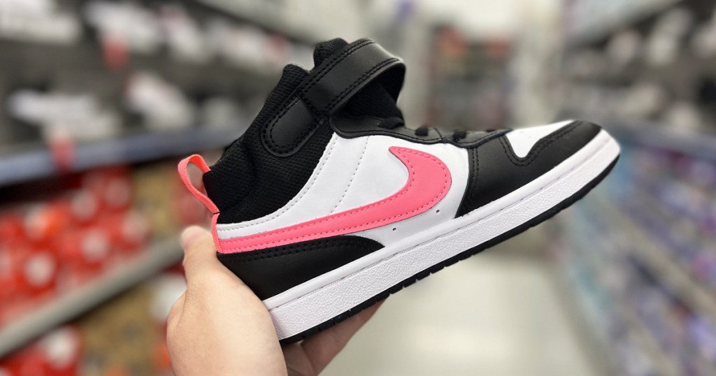 hand holding up a black, white, and pink nike kids sneaker