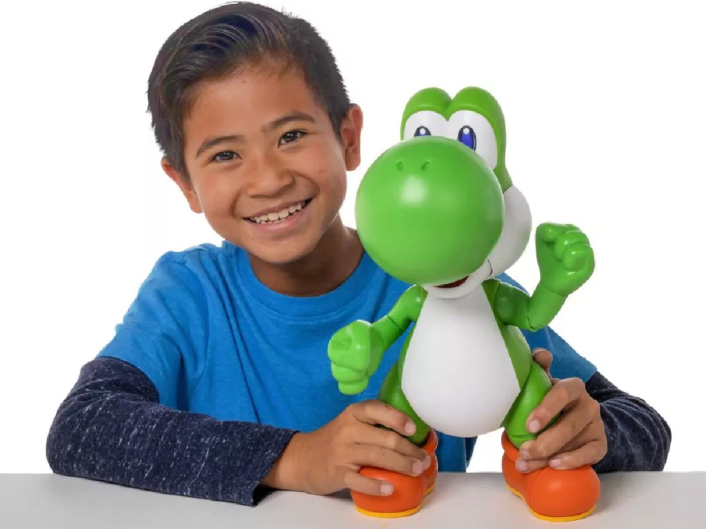 boy posing behind a Nintendo Super Mario yoshi figure