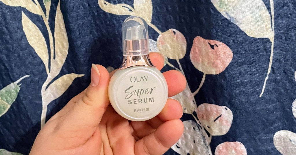 mini bottle of super serum in hand near quilted surface 