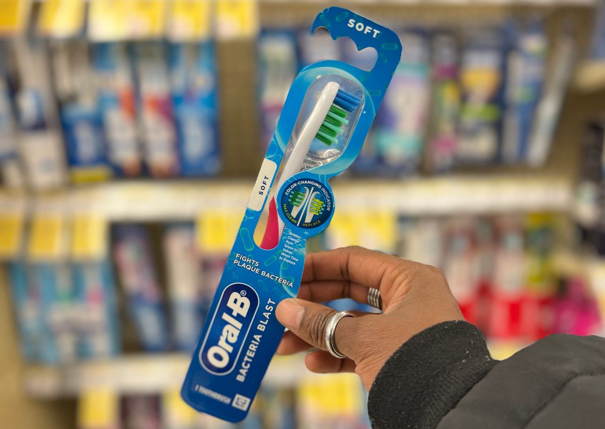 a womans hand holding a packaged toothbrush in a store 