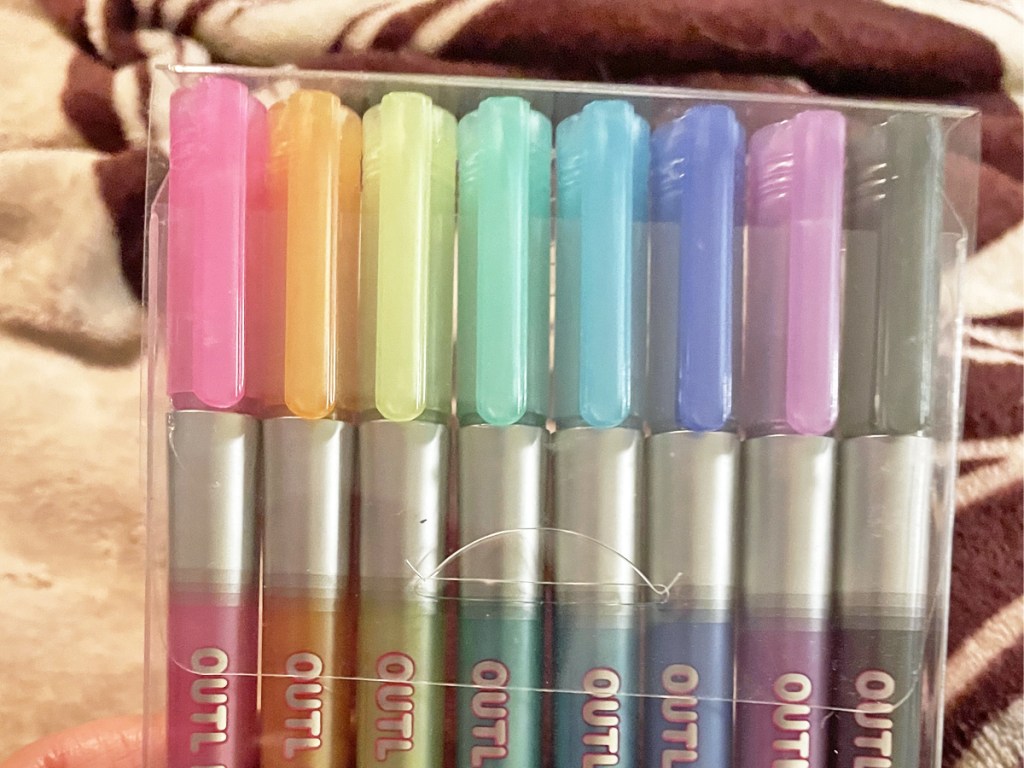 holding pack of pens in rainbow colors
