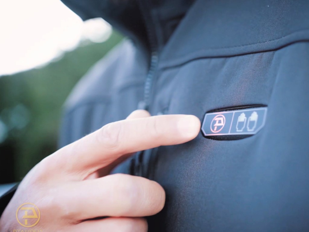 Person pushing button on black heated jacket