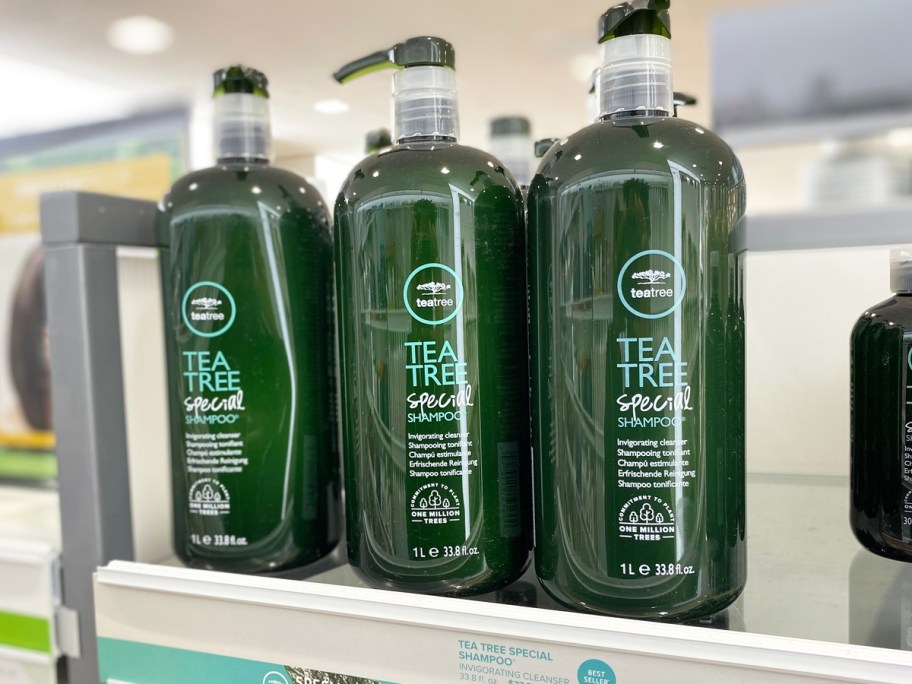 3 large green bottles of Paul Mitchell Tea Tree Shampoo on store shelf