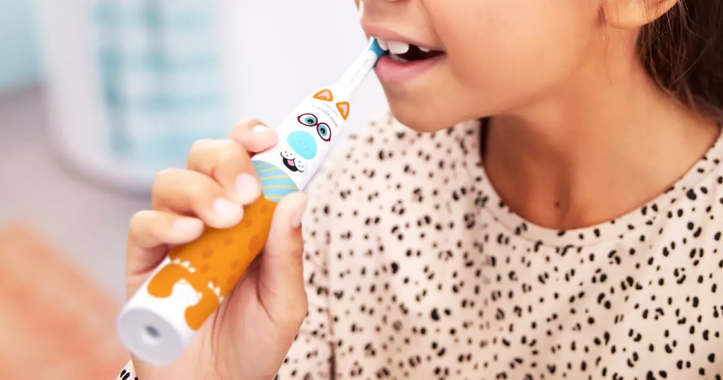 girl using an electric toothbrush covered in stickers