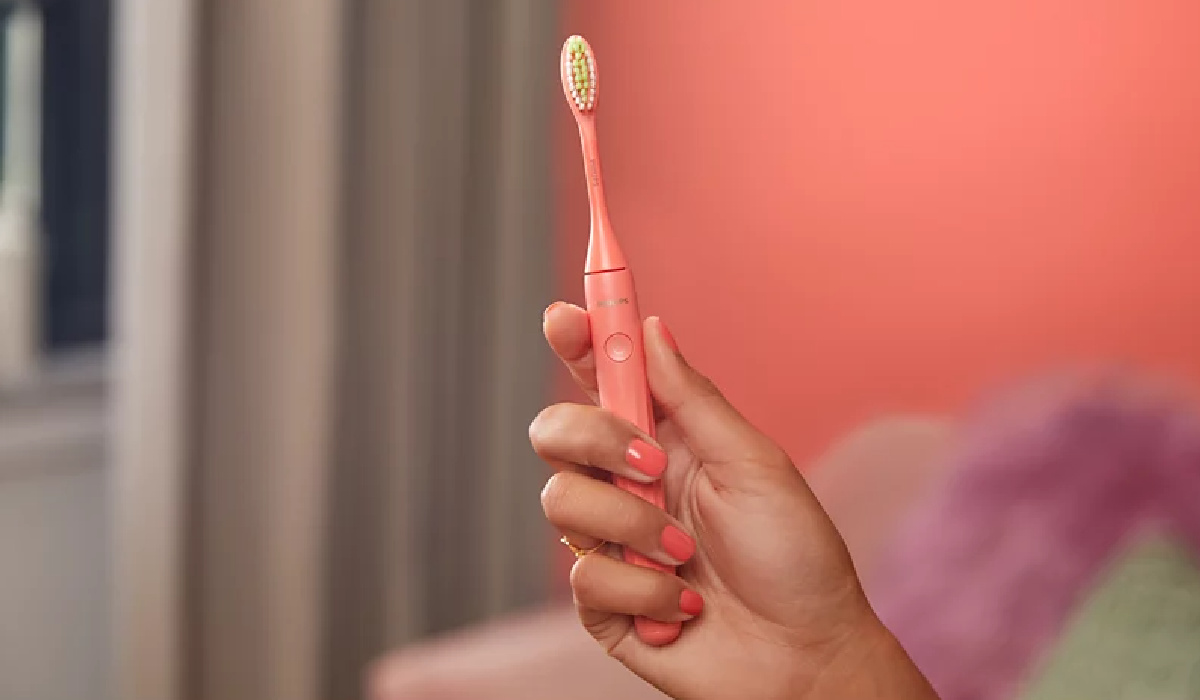 woman holding up a pink Philips toothbrush