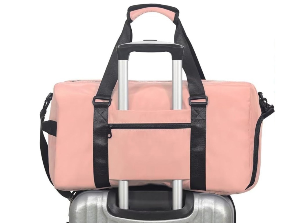 Pink colored duffel bag on top of roller bag