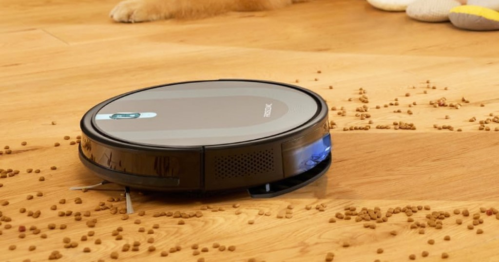 black robot vacuum cleaning up pet food spilled on wood floor