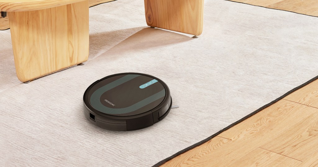 black robot vacuum on white area rug on wood floors