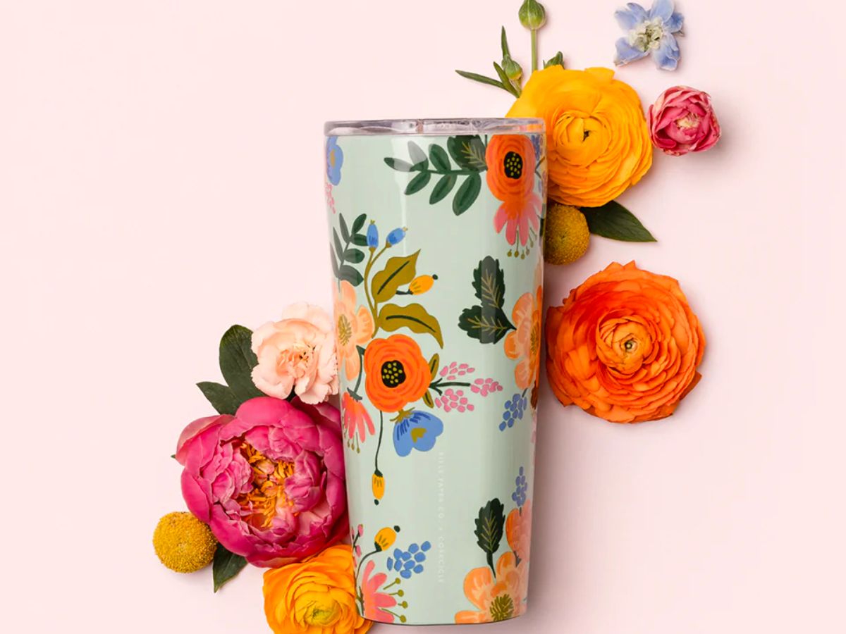 a floral print stainless steel tumbler surrounded by paper flowers on a pink background