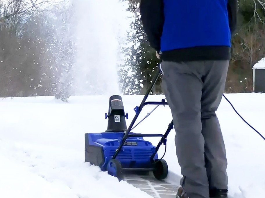 person using a blue snow blower to clear pathway