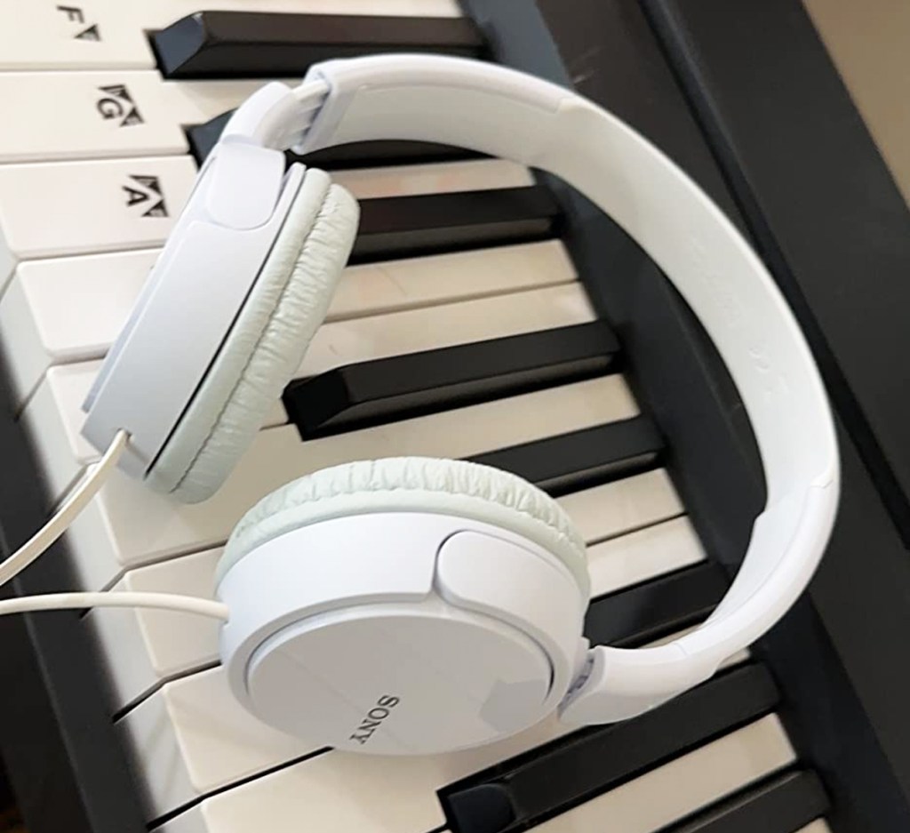 white sony headphones laying on a piano keyboard
