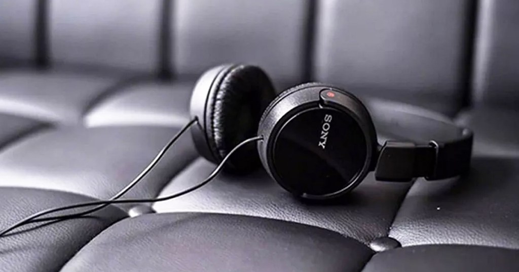 pair of black sony headphones on a black leather couch