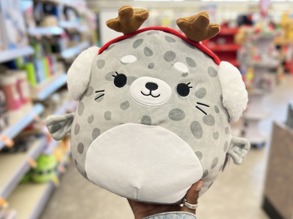 holding up a Christmas seal Squishmallows plush