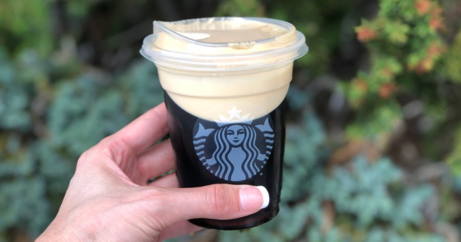 hand holding a cold Starbucks beverage in clear cup