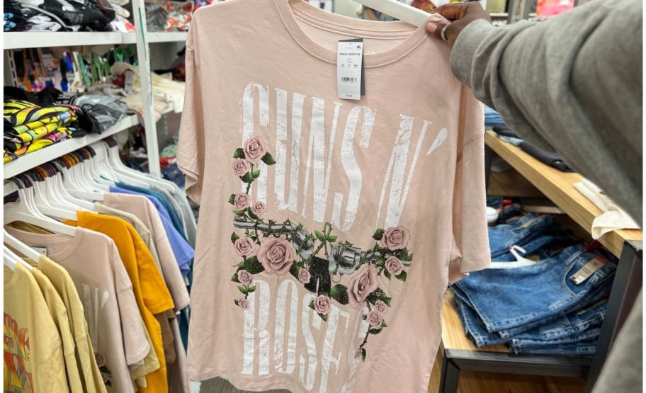 a womans hand holding a pink guns and rose graphic tee