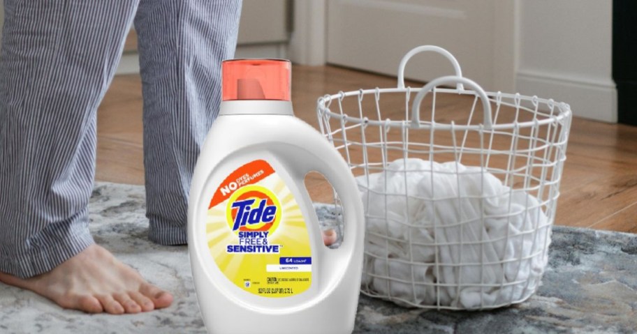 A bottle of Tide Simply Laundry Detergent next to a laundry basket of whites on the floor