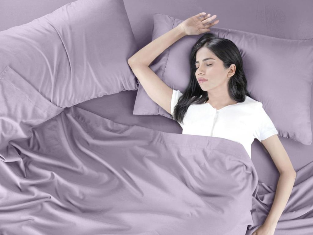A woman in bed with Utopia Bedding Sheets Set in purple