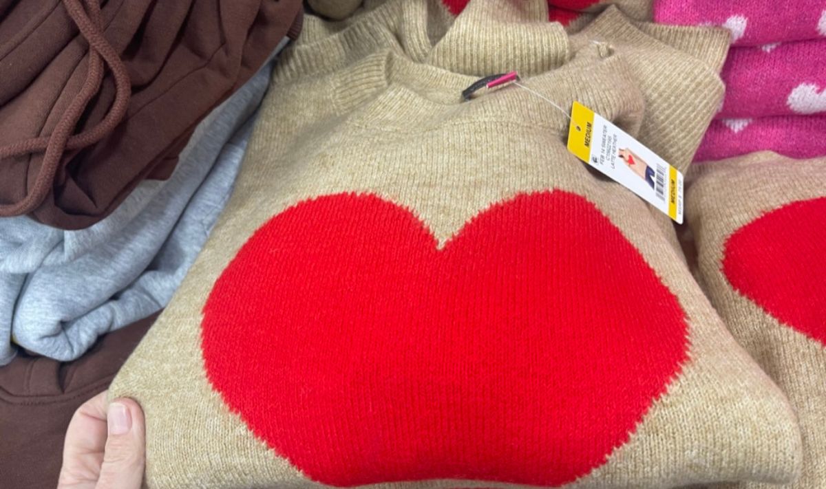 a womans hand displaying a Vince Camuto womens Valentines Day Sweater in khaki heather with a red heart