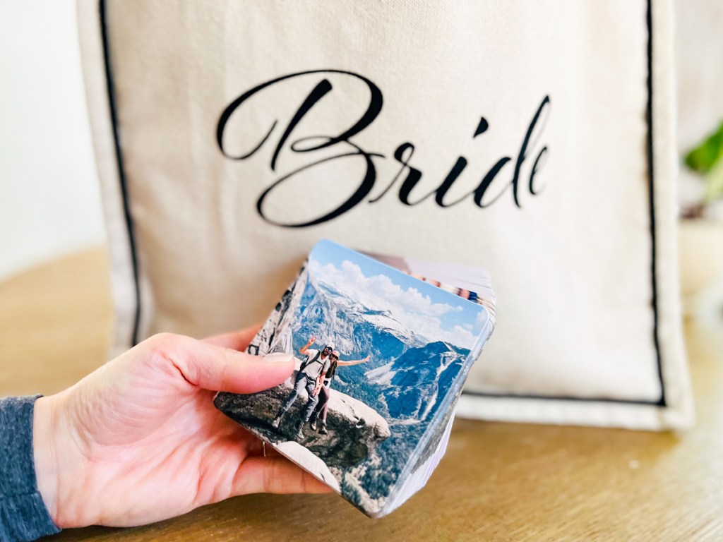 hand holding a stack of photo coasters near a bag that says bride