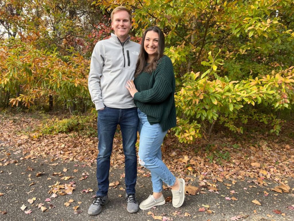 couple standing outside on street filled with fall leaves