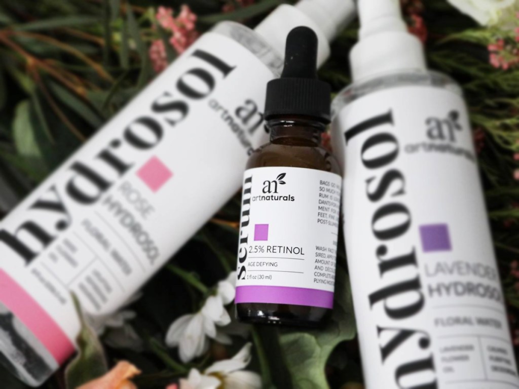 bottle of artnaturals Retinol Serum laying in flowers with two large facial spray bottles
