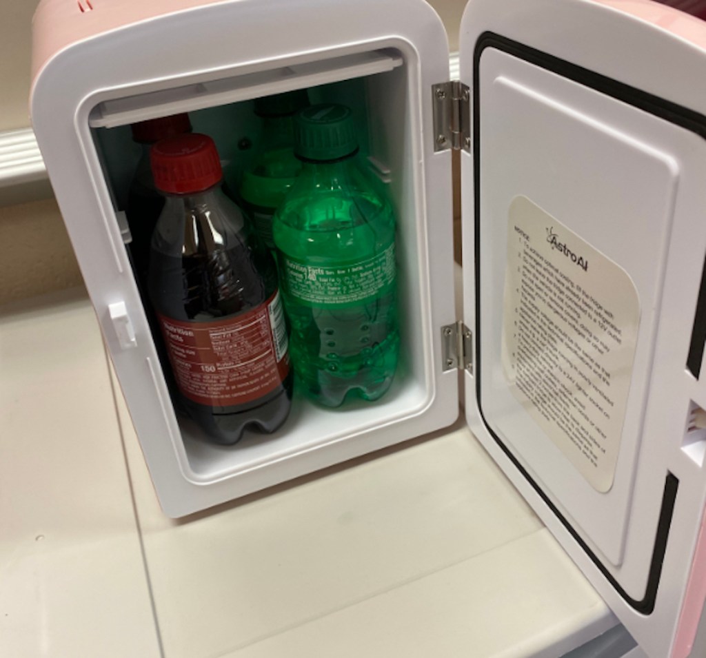 open mini fridge with soda bottles inside