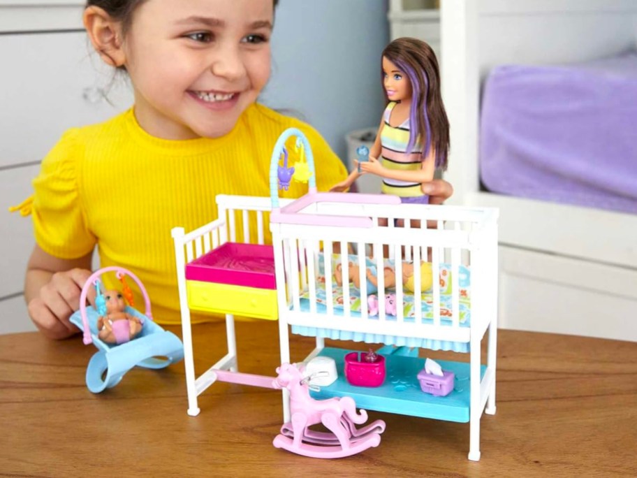 girl playing with barbie nursery set