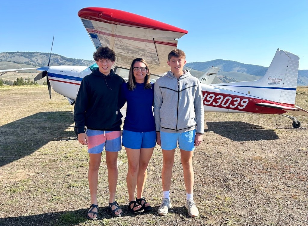 woman with boys standing outside in front of small airplane