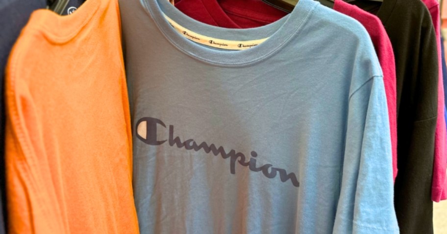 blue, orange, red, and black Champion logo tees on a clothing rack