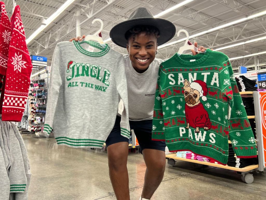 two christmas sweaters being held up in walmart