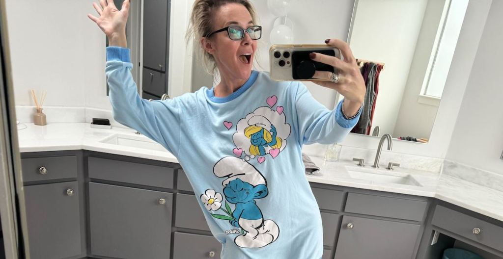 woman taking selfie in bathroom mirror wearing blue smurfs nightgown