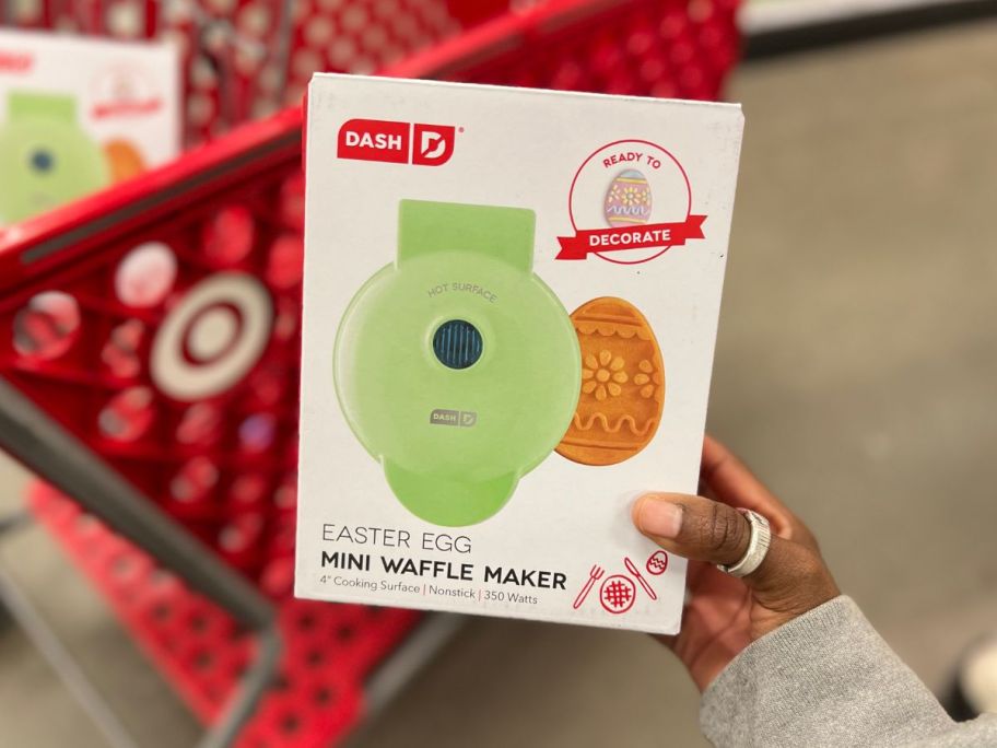 hand holding up easter waffle maker with cart in background