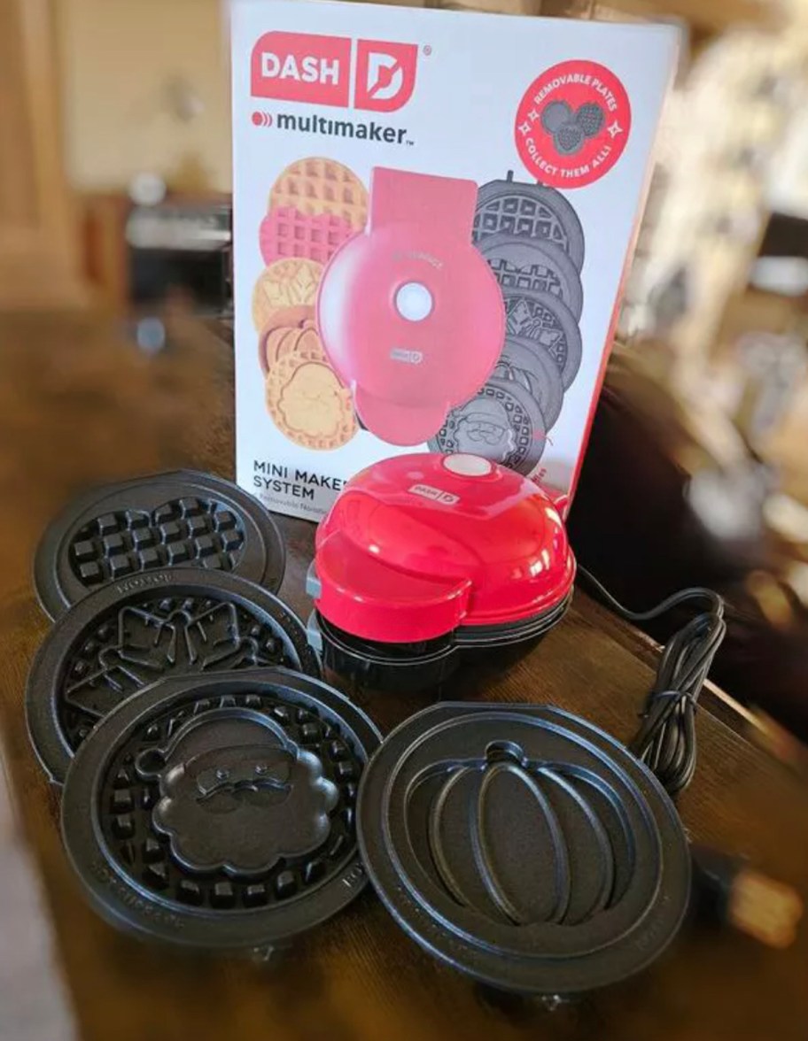 dash mini waffle maker with interchangeable plates sitting on wood table