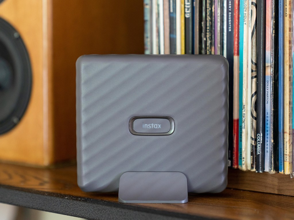 gray mini printer standing on shelf with records