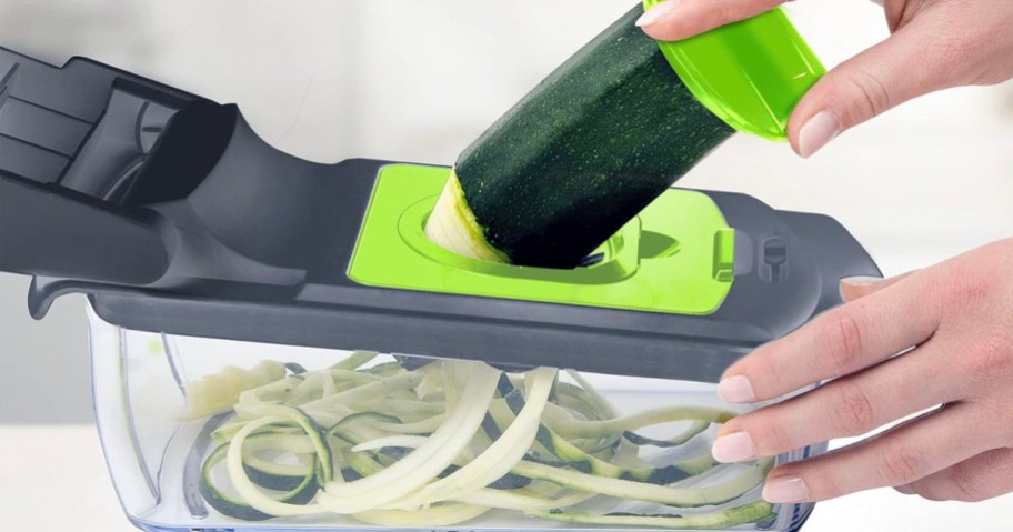 hand spiraling zucchini in gray and green vegetable chopper