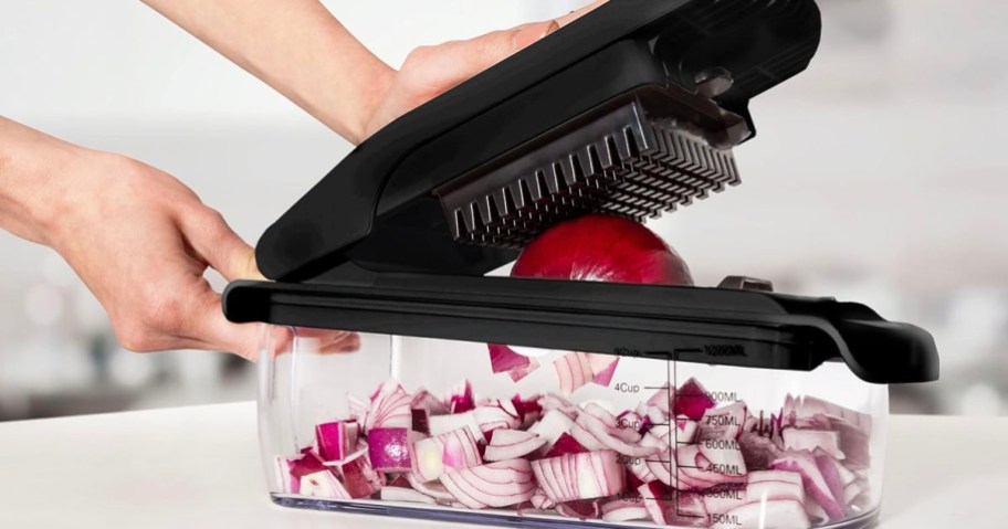 hand chopping red onion in vegetable chopper on countertop