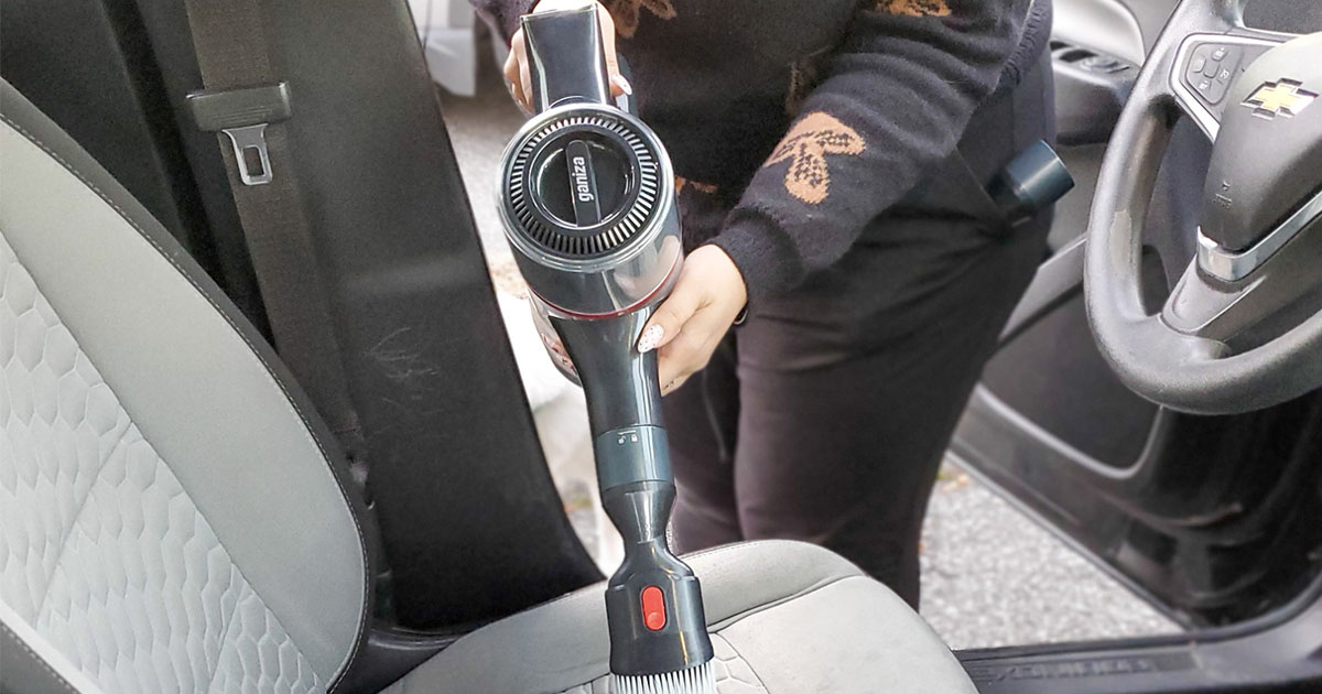 person cleaning carseat with cordless vacuum