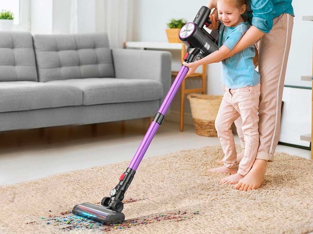 mom and child vacuuming rug with purple stick cordless vaccuum