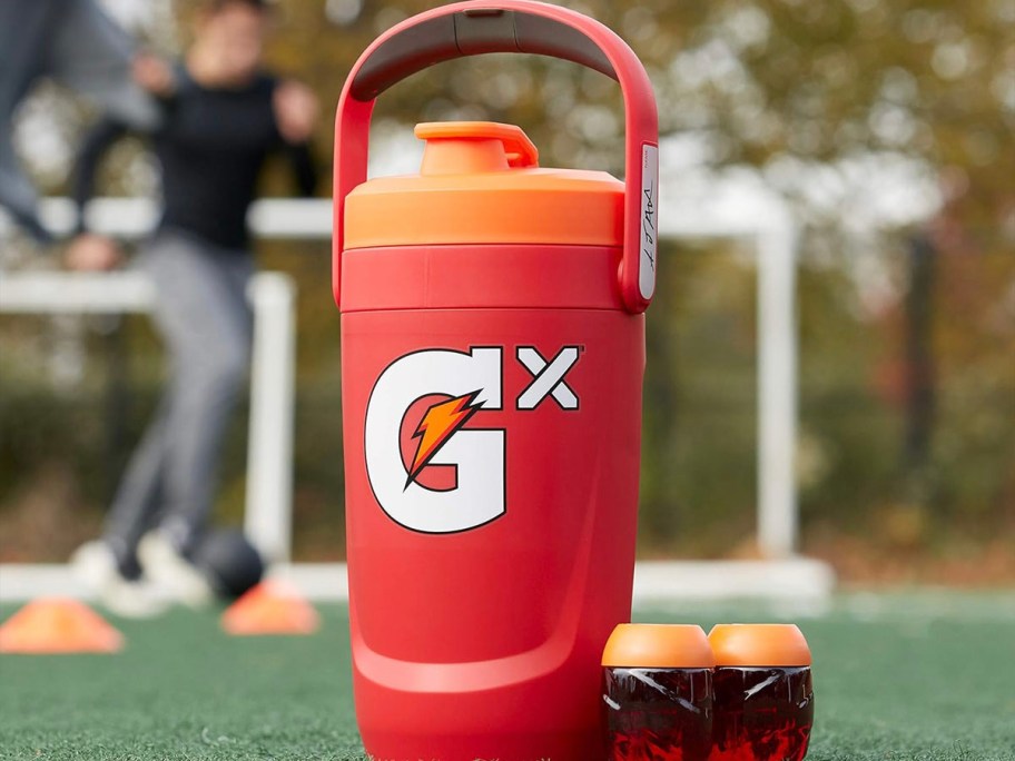 red gatorade jug sitting on grass with two pods