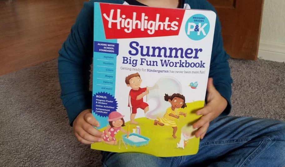 a kid holding a highlights summer big fun workbook