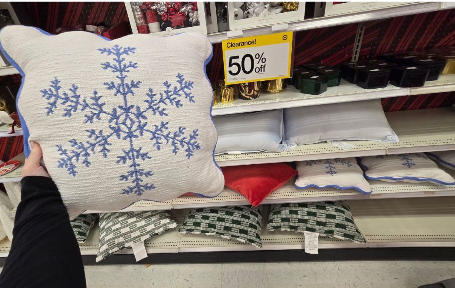 a womans hand holding a holiday throw pillow