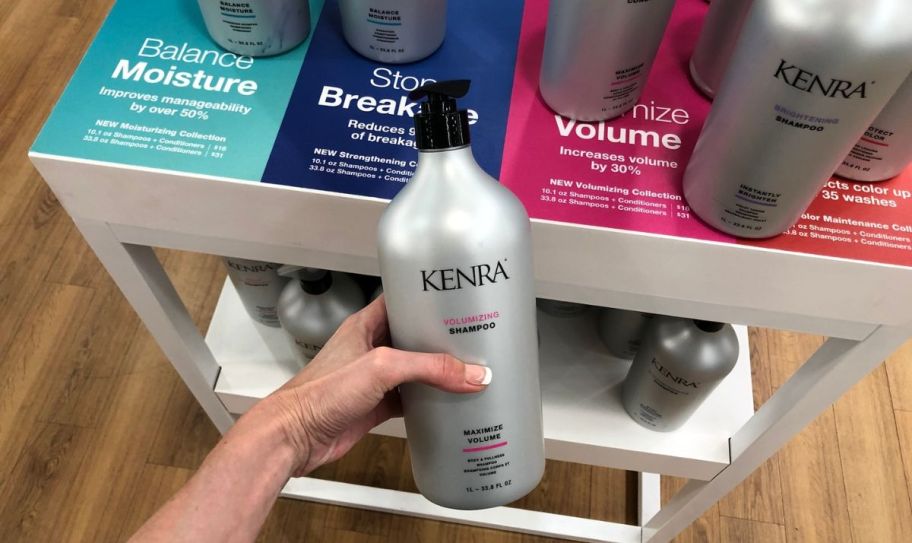 a womans hand holding a bottle of kenra shampoo