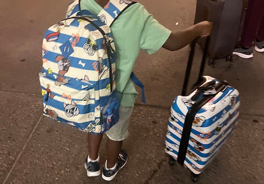 boy with book bag pushing coordinating carry on suitcase