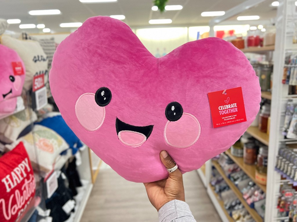 holding up a pink heart pillow