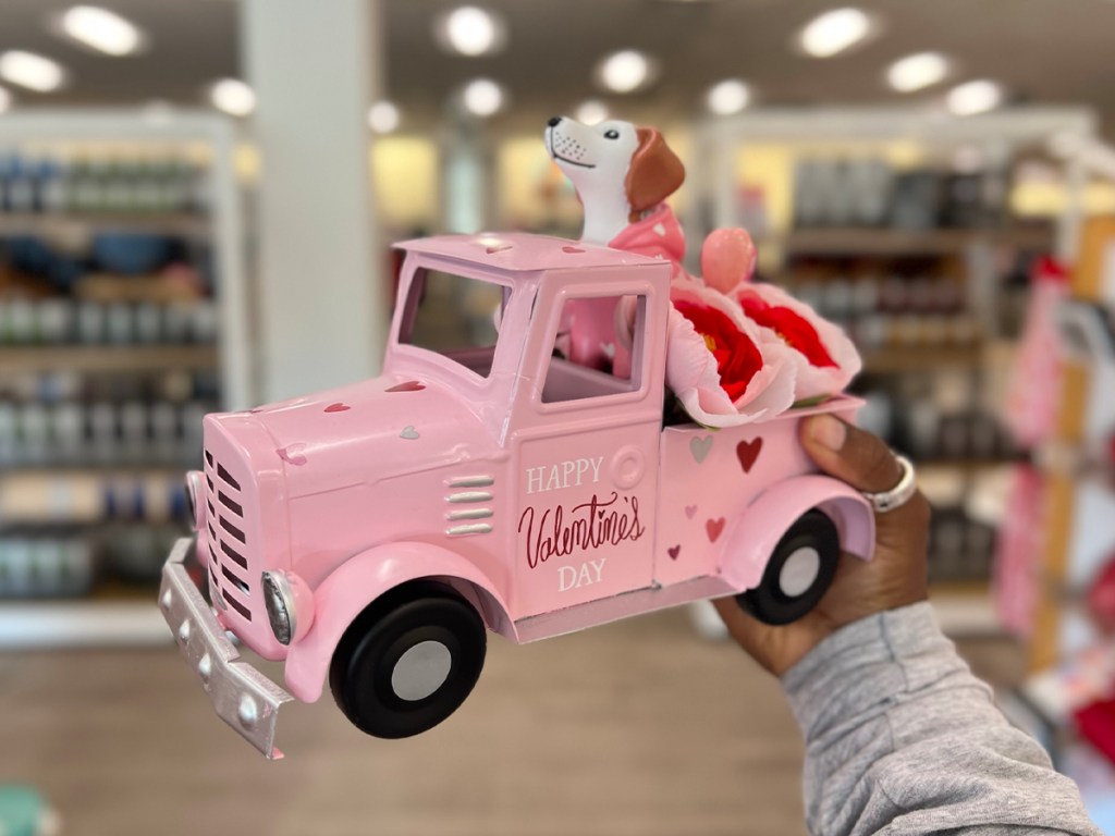 hand holding pink valentines day truck with dog in the back