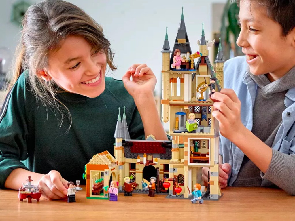 two kids playing with LEGO Hogwarts set