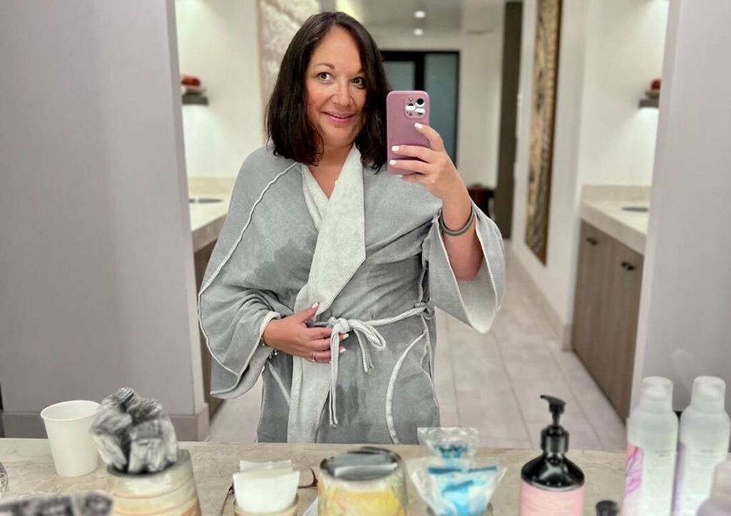 woman holding a phone taking mirror selfie at spa countertop